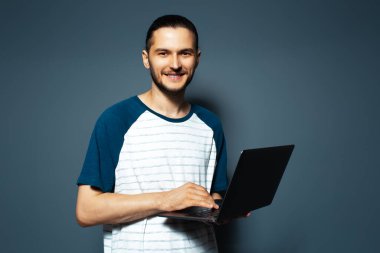 Mavi arka planda elinde tuttuğu bilgisayarın stüdyo portresi..