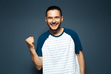 Öyle mi? Genç mutlu adamın stüdyo portresi zaferini kutluyor. Mavi arkaplan.