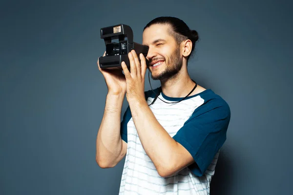 Studio portrait of young man photographer making photo with polaroid camera.