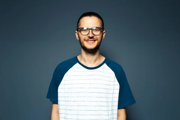 Studio portrait of smiling guy in shirt on blue background, wearing eyeglasses.