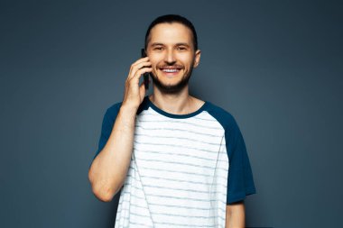 Studio portrait of young smiling man, talking on the smartphone.  