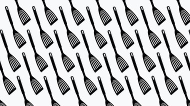 Pattern of black plastic turner spatula on white background.