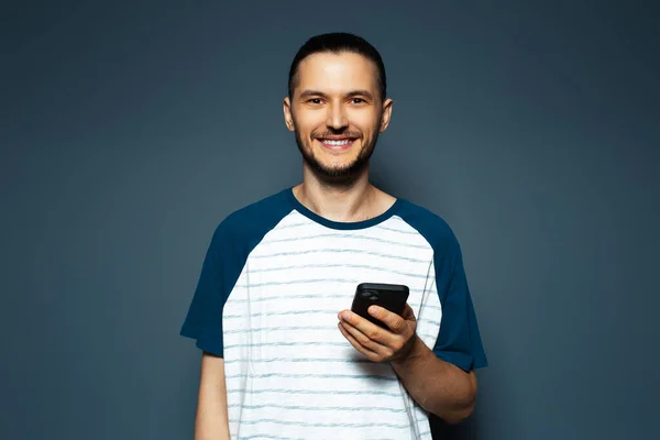 Studio Portrait Young Smiling Man Holding Smartphone Stockfoto