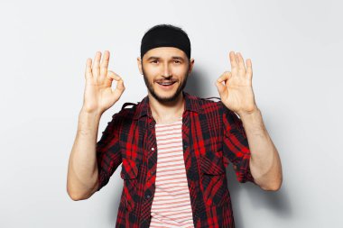 Studio portrait of young happy guy showing ok gestures on  white background.
