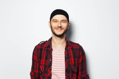 Studio portrait of young smiling attractive guy, wearing red plaid shirt and black headband.