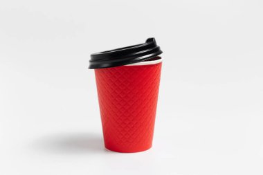 Close-up of paper cup with black plastic lid for coffee takeaway of red color isolated on white studio background.