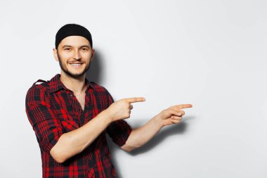 Studio portrait of young smiling guy, pointing to the left. Copy space idea.