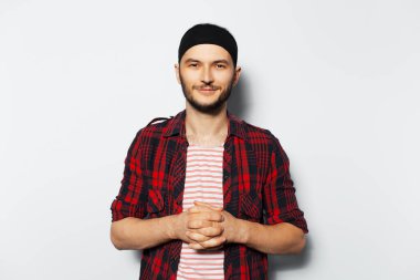 Studio portrait of young attractive guy, wearing red plaid shirt and black headband.