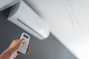 Male hand holding remote control of the air conditioner.