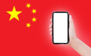 Close-up of male hand holding smartphone with blank on screen, on background of blurred flag of China.