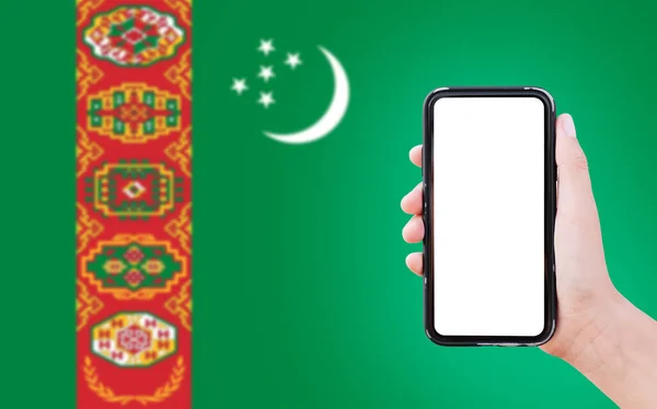 Чоловік Тримає Смартфон Порожнім Екраном Фоні Розмитого Прапора Туркменістану — стокове фото