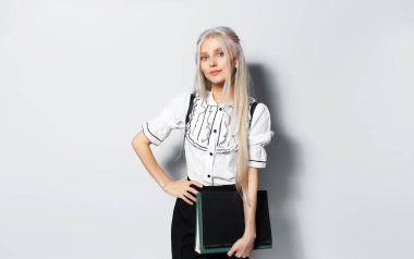 Studio portrait of young blonde beautiful girl holding a folders in hand, on white background.