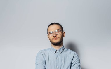 Studio portrait of young confident man wearing eyeglasses and blue t-shirt on white background.