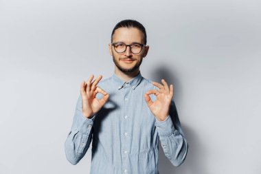 Beyaz arka planda iyi niyet gösteren kendine güvenen genç bir adamın stüdyo portresi.