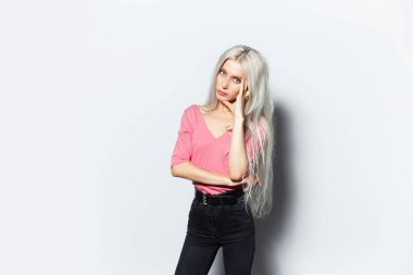 Beyaz arka planda Pastel pembe gömlek giyen genç sarışın kızın stüdyo portresi..