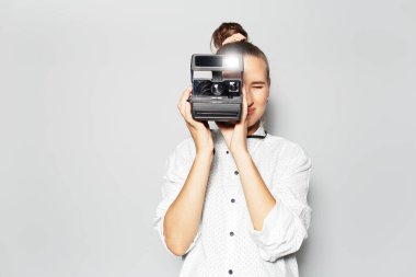 Genç gülümseyen kızın stüdyo portresi, fotoğrafçı klasik kamerayla fotoğraf çekiyor..