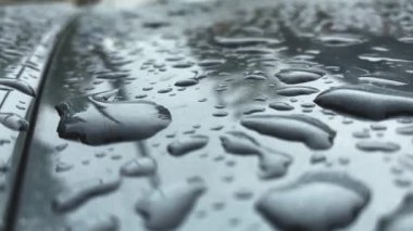 Gri yüzeyde yağmurdan sonra su damlalarının yakın plan görüntüsü.