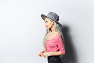 Stüdyoda, kulaklıklı, beyaz arka planda gri şapkalı ve pembe gömlekli güzel bir kızın portresi..