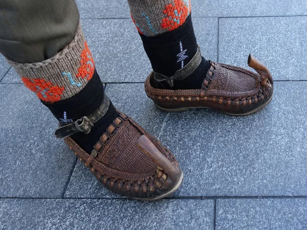 Man wears  traditional handcrafted leather peasant shoes, with decorated wool socks on the feet