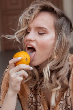 Limonlu ve leopar desenli sarı saçlı şık bir kızın sokak portresi.