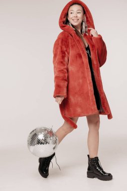 Beyaz bir arka planda poz veren kürklü güzel ve şık bir kız.