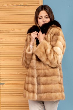 Koyu renk saçlı güzel bir kız kürk manto giymiş.