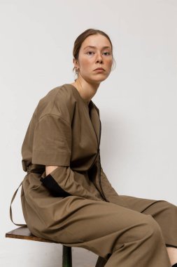 Stüdyoda şık ve güzel bir kız beton duvara karşı poz veriyor.