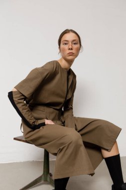 Stüdyoda şık ve güzel bir kız beton duvara karşı poz veriyor.