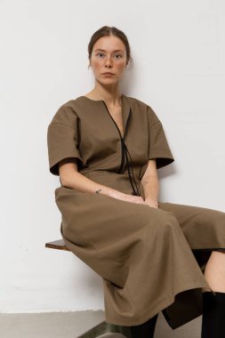 Stüdyoda şık ve güzel bir kız beton duvara karşı poz veriyor.