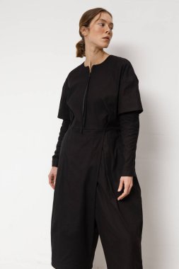 Stüdyoda şık ve güzel bir kız beton duvara karşı poz veriyor.