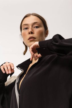 Stüdyoda şık ve güzel bir kız beton duvara karşı poz veriyor.