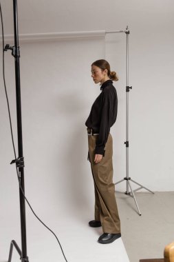 Stüdyoda şık ve güzel bir kız beton duvara karşı poz veriyor.