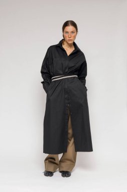 Stüdyoda şık ve güzel bir kız beton duvara karşı poz veriyor.