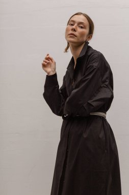 Stüdyoda şık ve güzel bir kız beton duvara karşı poz veriyor.