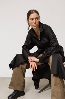 Stüdyoda şık ve güzel bir kız beton duvara karşı poz veriyor.