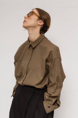 Stüdyoda şık ve güzel bir kız beton duvara karşı poz veriyor.