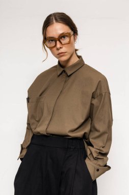 Stüdyoda şık ve güzel bir kız beton duvara karşı poz veriyor.