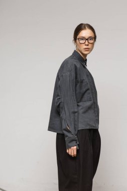 Stüdyoda şık ve güzel bir kız beton duvara karşı poz veriyor.