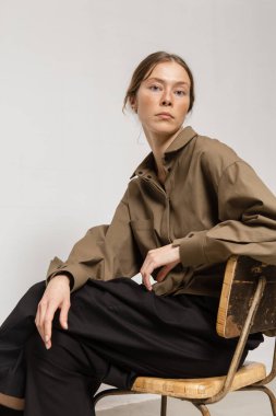 Stüdyoda şık ve güzel bir kız beton duvara karşı poz veriyor.