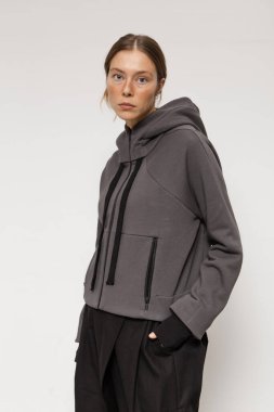 Stüdyoda şık ve güzel bir kız beton duvara karşı poz veriyor.