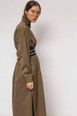 Stüdyoda şık ve güzel bir kız beton duvara karşı poz veriyor.