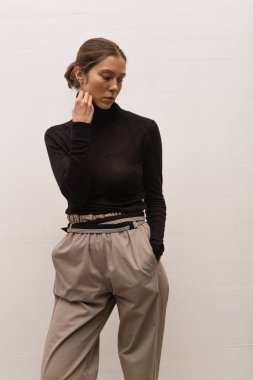 Stüdyoda şık ve güzel bir kız beton duvara karşı poz veriyor.