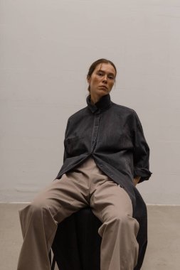 Stüdyoda şık ve güzel bir kız beton duvara karşı poz veriyor.