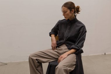 Stüdyoda şık ve güzel bir kız beton duvara karşı poz veriyor.