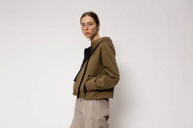 Stüdyoda şık ve güzel bir kız beton duvara karşı poz veriyor.