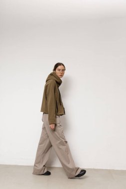 Stüdyoda şık ve güzel bir kız beton duvara karşı poz veriyor.