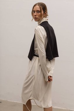 Stüdyoda şık ve güzel bir kız beton duvara karşı poz veriyor.