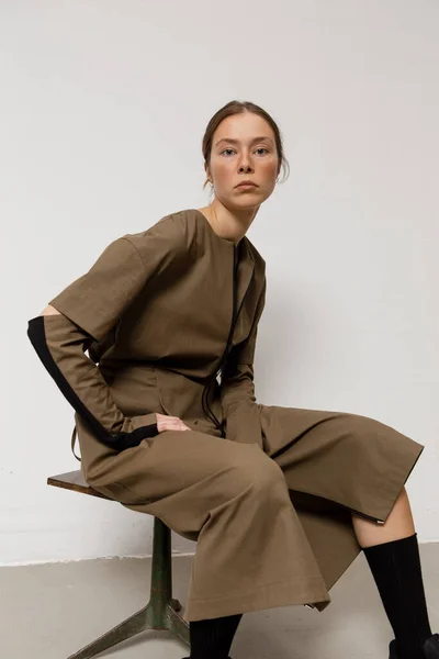 Stüdyoda şık ve güzel bir kız beton duvara karşı poz veriyor.