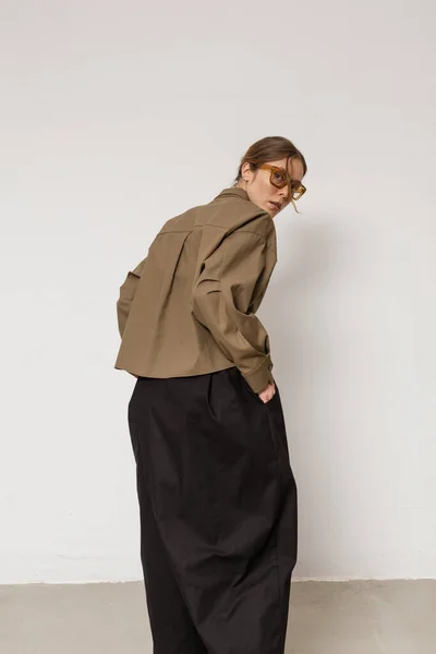 Stüdyoda şık ve güzel bir kız beton duvara karşı poz veriyor.