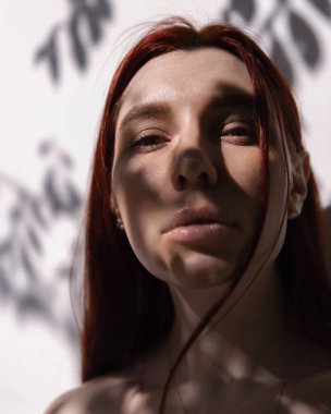 Yüzünde bir ağacın gölgesi ve kızıl saçlı güzel bir kızın yaz portresi.